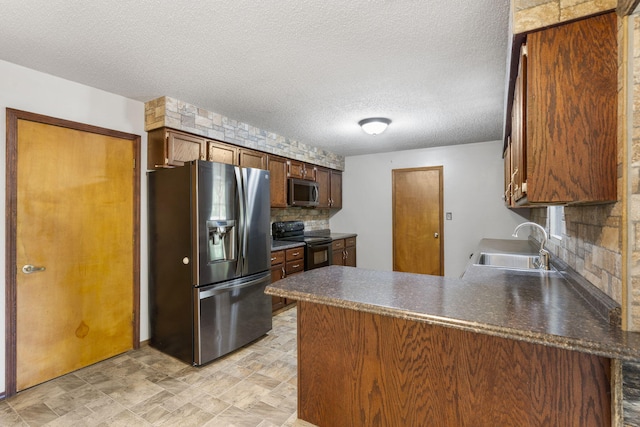 1801 W Cherokee St, Springfield, MO 65807 - kitchen with appliances with stainless steel finishes, a peninsula, decorative backsplash, a textured ceiling, and dark countertops