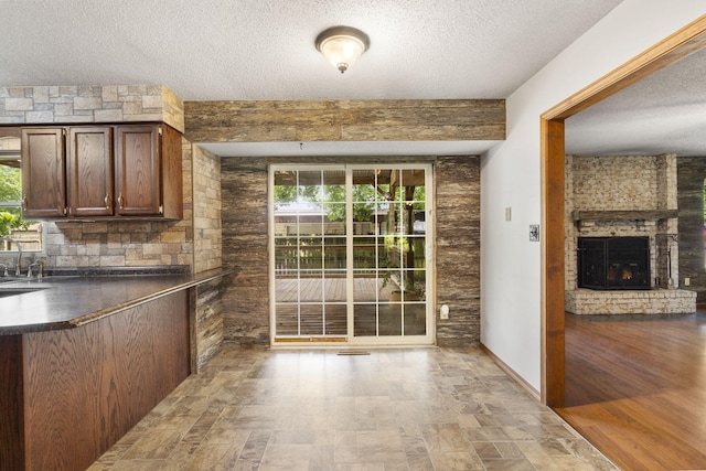1801 W Cherokee St, Springfield, MO 65807 - kitchen featuring dark countertops, a textured ceiling, stone finish floors, a brick fireplace, and plenty of natural light