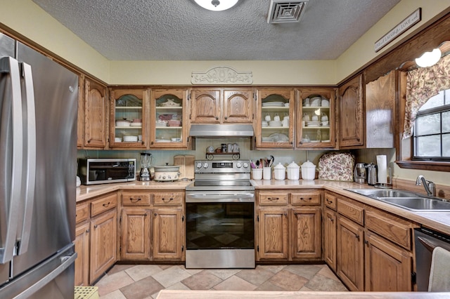1706 Ankney Pl, Neosho, MO 64850 - kitchen featuring appliances with stainless steel finishes, under cabinet range hood, light countertops, brown cabinets, and a textured ceiling