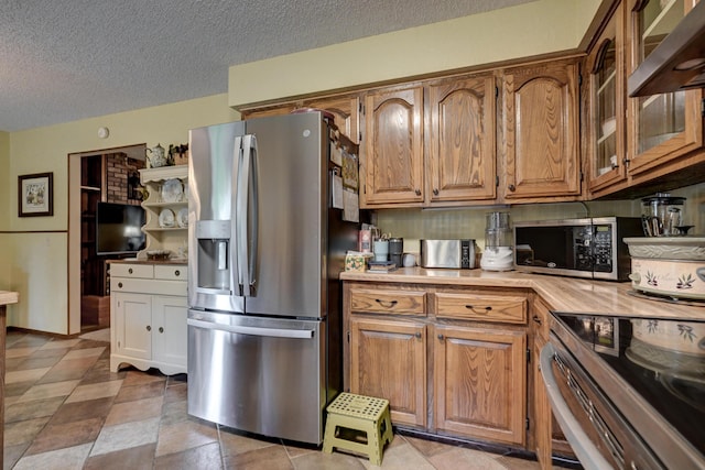 1706 Ankney Pl, Neosho, MO 64850 - kitchen featuring appliances with stainless steel finishes, wall chimney range hood, light countertops, a textured ceiling, and brown cabinets
