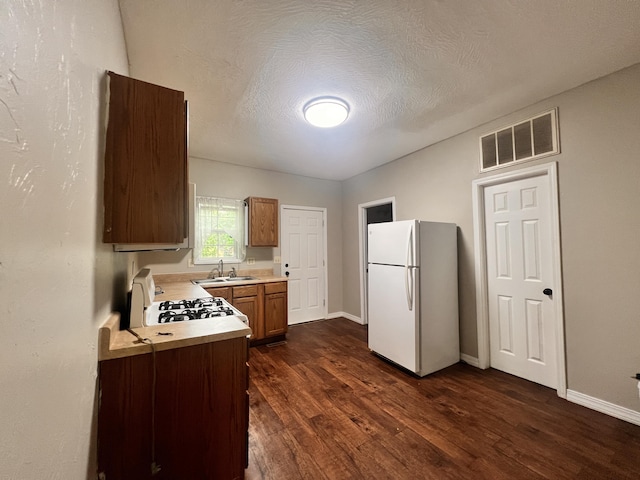 1322 W Atlantic St, Springfield, MO 65803 - kitchen with white appliances, dark wood finished floors, light countertops, brown cabinets, and a textured ceiling