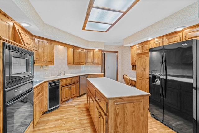 4081 E Kingsbury St, Springfield, MO 65809 - kitchen with black appliances, wallpapered walls, light wood-style floors, a kitchen island, and light countertops
