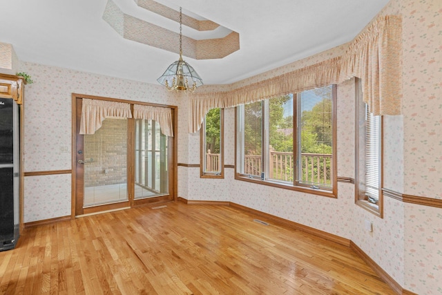 4081 E Kingsbury St, Springfield, MO 65809 - unfurnished dining area featuring wallpapered walls, light wood-style flooring, a chandelier, and a tray ceiling