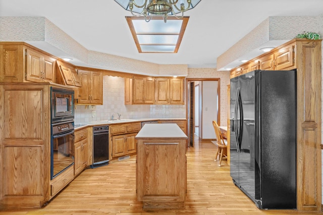4081 E Kingsbury St, Springfield, MO 65809 - kitchen with black appliances, a kitchen island, wallpapered walls, light wood-style flooring, and light countertops