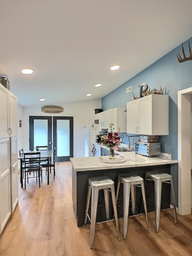 556 Carter 309, Van Buren, MO 63965 - kitchen with a peninsula, a breakfast bar area, light wood-style floors, white cabinets, and light stone counters