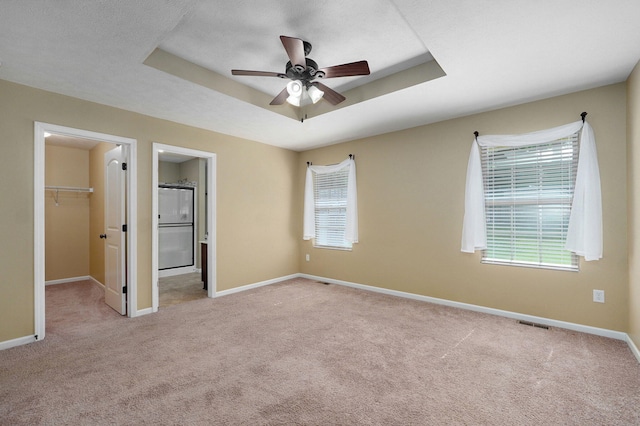 5834 Geranium Ln, Battlefield, MO 65619 - unfurnished bedroom featuring a walk in closet, light colored carpet, ensuite bath, a raised ceiling, and ceiling fan