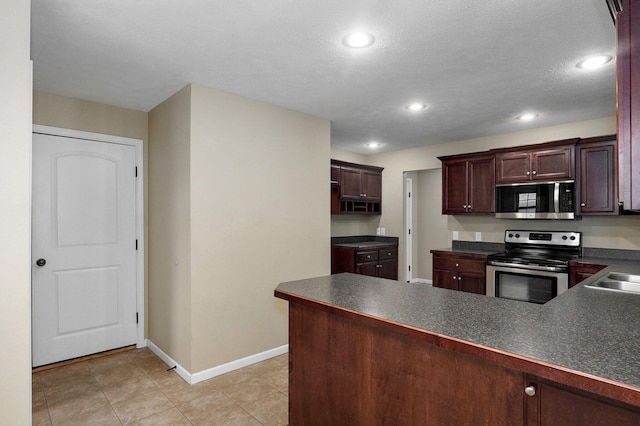 5834 Geranium Ln, Battlefield, MO 65619 - kitchen with appliances with stainless steel finishes, dark countertops, recessed lighting, light tile patterned floors, and a peninsula