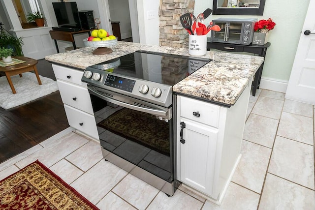 628 W Lynn St, Springfield, MO 65802 - kitchen with stainless steel electric range oven, white cabinets, light stone countertops, and light tile patterned flooring