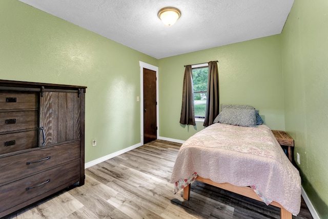 1604 E Sycamore St, Ozark, MO 65721 - bedroom featuring light wood-type flooring, a textured ceiling, and a textured wall