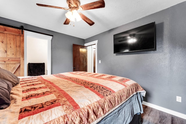 1604 E Sycamore St, Ozark, MO 65721 - bedroom featuring dark wood finished floors, a barn door, a textured wall, and a ceiling fan