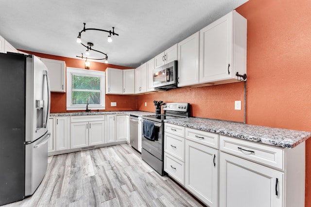 1604 E Sycamore St, Ozark, MO 65721 - kitchen featuring stainless steel appliances, white cabinetry, light wood-type flooring, and a textured wall