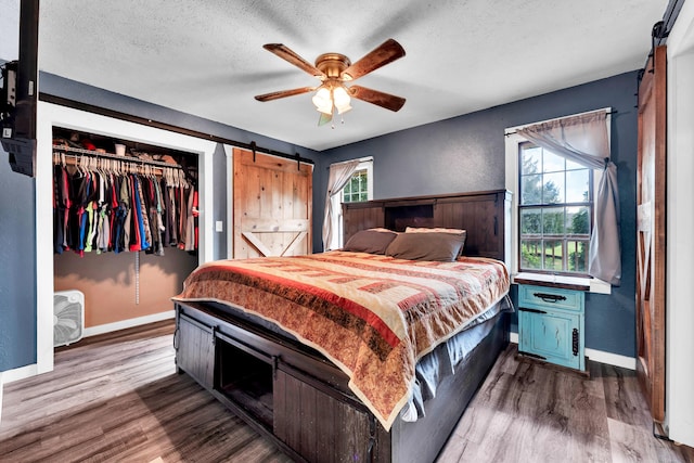1604 E Sycamore St, Ozark, MO 65721 - bedroom with a barn door, a closet, dark wood-style floors, a textured ceiling, and a ceiling fan