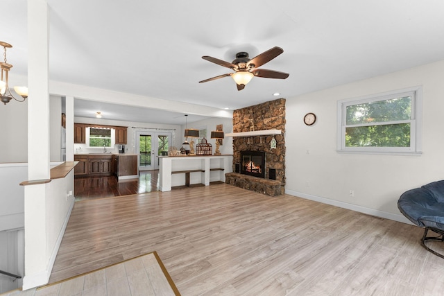 189 Pierce Pl, Forsyth, MO 65653 - living room featuring wood finished floors, a ceiling fan, a stone fireplace, and a chandelier