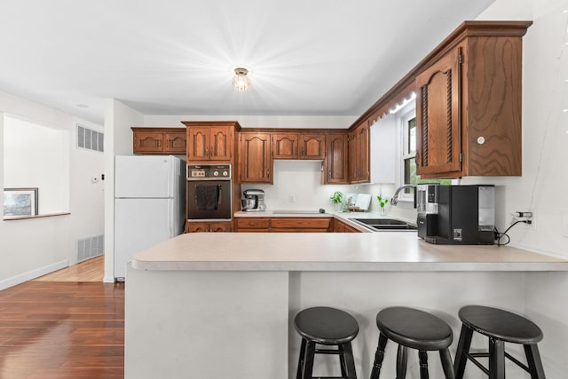 189 Pierce Pl, Forsyth, MO 65653 - kitchen featuring freestanding refrigerator, black oven, a peninsula, light countertops, and dark wood-style floors