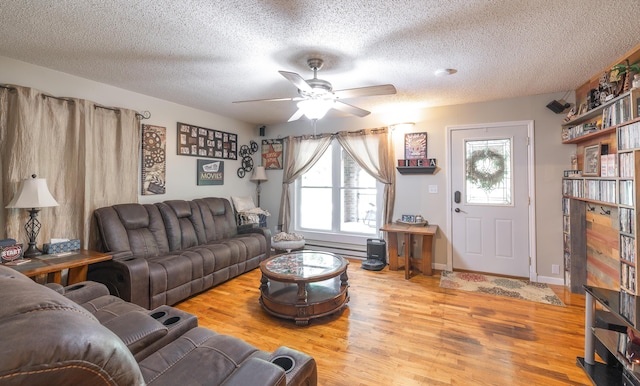 11240 State Hwy E, Rolla, MO 65401 - living room featuring wood finished floors, a ceiling fan, a textured ceiling, and a baseboard radiator
