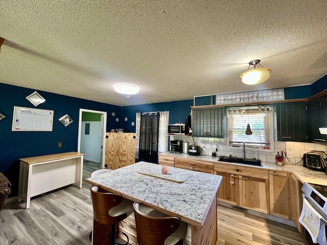 817 Fillmore St, Mount Vernon, MO 65712 - kitchen featuring light countertops, decorative backsplash, light wood-type flooring, a center island, and a textured ceiling