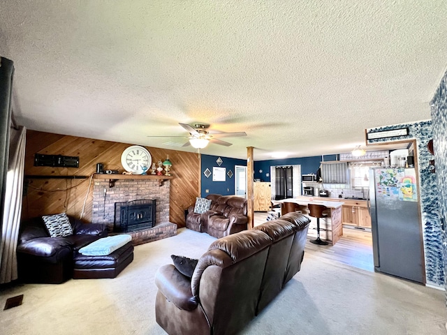 817 Fillmore St, Mount Vernon, MO 65712 - living room featuring wooden walls, ceiling fan, a brick fireplace, a textured ceiling, and light carpet