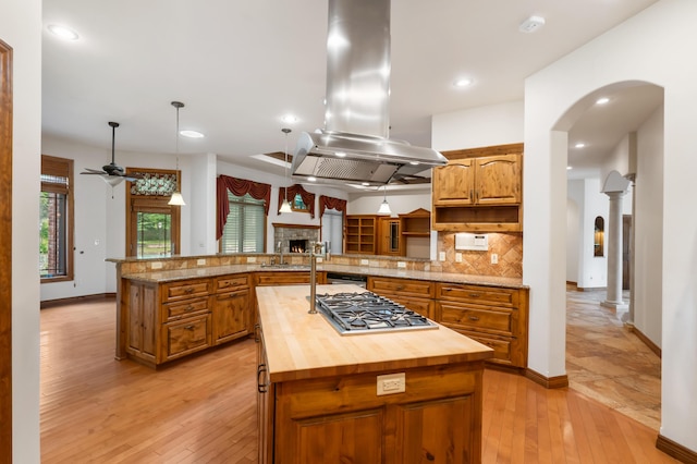 744 Seven Pines Dr, Saddlebrooke, MO 65630 - kitchen featuring island range hood, stainless steel gas cooktop, brown cabinetry, open shelves, and a kitchen island