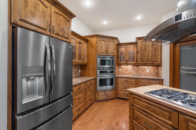 744 Seven Pines Dr, Saddlebrooke, MO 65630 - kitchen with stainless steel appliances, exhaust hood, brown cabinets, light wood-style floors, and glass insert cabinets