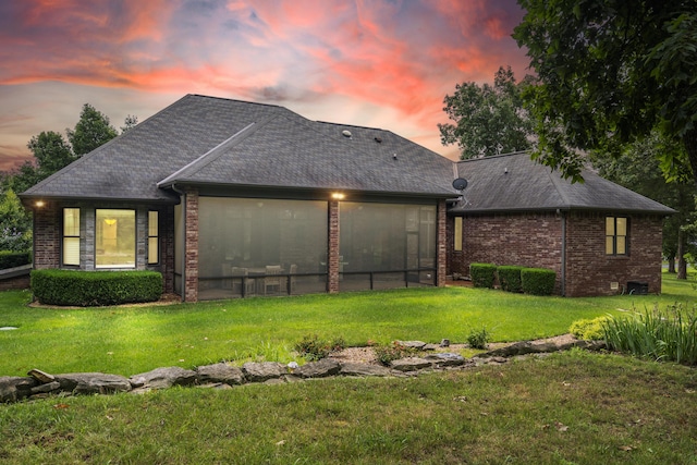 744 Seven Pines Dr, Saddlebrooke, MO 65630 - back of property at dusk featuring a yard, an attached garage, brick siding, and roof with shingles
