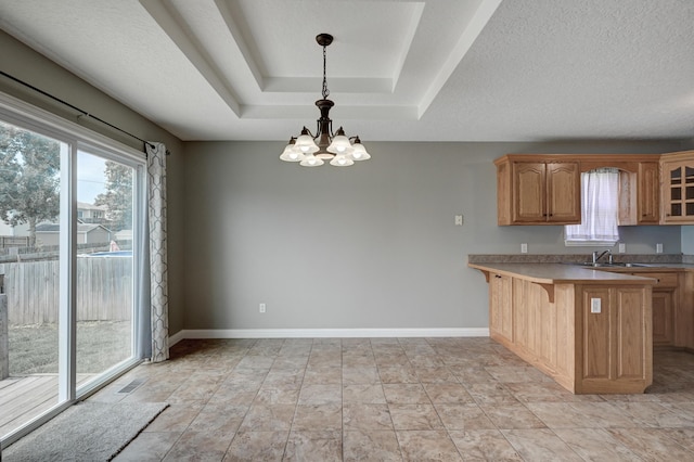 4406 W 28th St, Joplin, MO 64804 - kitchen with a chandelier, a breakfast bar, hanging light fixtures, a peninsula, and glass insert cabinets