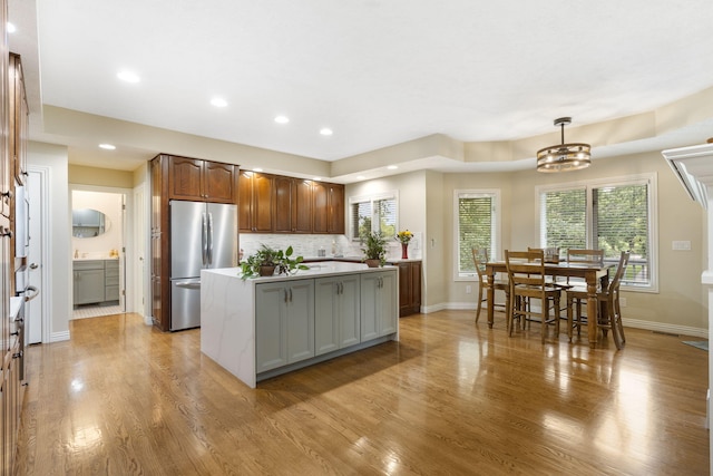3314 Winged Foot Dr, Nixa, MO 65714 - kitchen featuring freestanding refrigerator, a kitchen island, light countertops, light wood-style flooring, and decorative backsplash