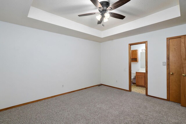 2816 N Pierce Ave, Springfield, MO 65803 - unfurnished bedroom featuring a tray ceiling, light carpet, ensuite bathroom, and a ceiling fan