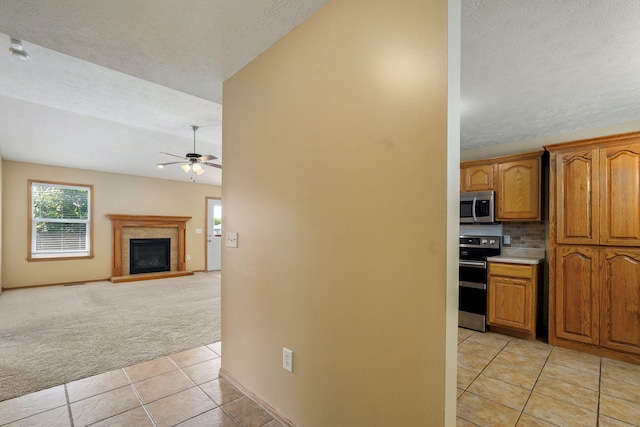 844 S Natalie Ave, Springfield, MO 65802 - kitchen featuring stainless steel appliances, light tile patterned floors, light carpet, ceiling fan, and a textured ceiling