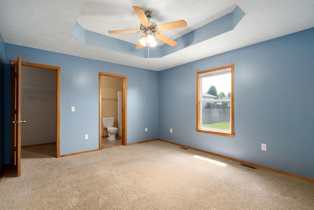 844 S Natalie Ave, Springfield, MO 65802 - unfurnished bedroom featuring a tray ceiling, a spacious closet, carpet flooring, ensuite bath, and ceiling fan