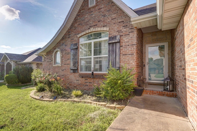 5055 E Cherry Pl, Springfield, MO 65809 - view of exterior entry with brick siding, a lawn, and roof with shingles