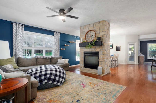 5055 E Cherry Pl, Springfield, MO 65809 - living area featuring a textured ceiling, wood finished floors, a ceiling fan, and a stone fireplace