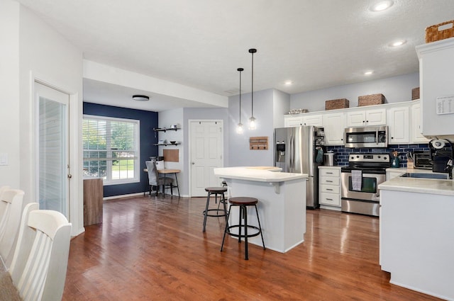 5055 E Cherry Pl, Springfield, MO 65809 - kitchen with stainless steel appliances, a kitchen island, white cabinets, a kitchen bar, and dark wood finished floors