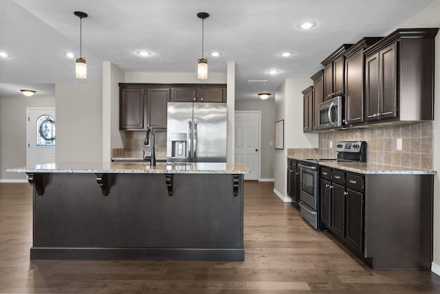 1950 S Trinidad Dr, Ozark, MO 65721 - kitchen featuring stainless steel appliances, dark brown cabinetry, a kitchen bar, light stone countertops, and dark wood-type flooring