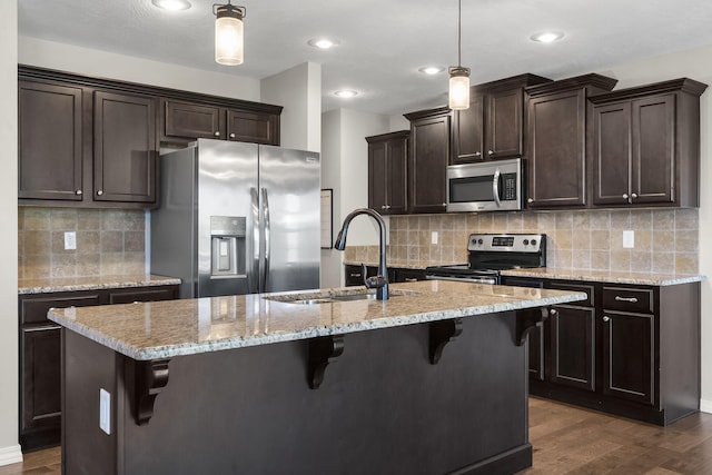 1950 S Trinidad Dr, Ozark, MO 65721 - kitchen featuring stainless steel appliances, dark brown cabinets, dark wood finished floors, tasteful backsplash, and a kitchen island with sink