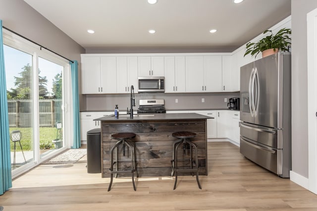 622 N Dean Ln, Republic, MO 65738 - kitchen featuring appliances with stainless steel finishes, dark countertops, light wood-type flooring, white cabinets, and recessed lighting