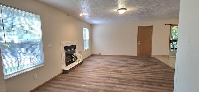 2830 N Washington Ave, Springfield, MO 65803 - unfurnished living room with wood finished floors, a tiled fireplace, and a textured ceiling