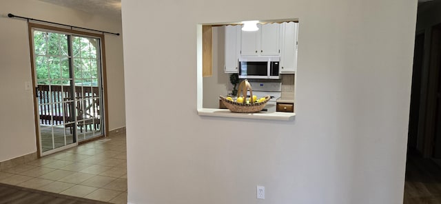 2830 N Washington Ave, Springfield, MO 65803 - kitchen with white microwave, white cabinets, decorative backsplash, stove, and light countertops