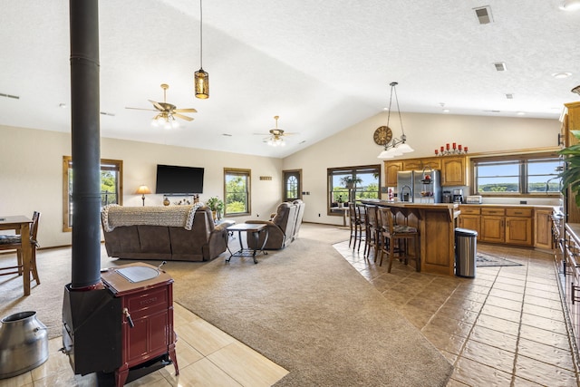 14410 Native Dr, Phillipsburg, MO 65722 - living room featuring a wood stove, light carpet, lofted ceiling, and ceiling fan