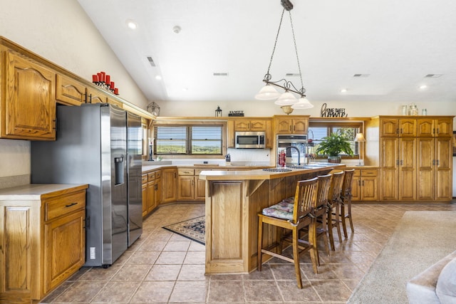 14410 Native Dr, Phillipsburg, MO 65722 - kitchen featuring stainless steel appliances, a center island with sink, light countertops, brown cabinetry, and lofted ceiling