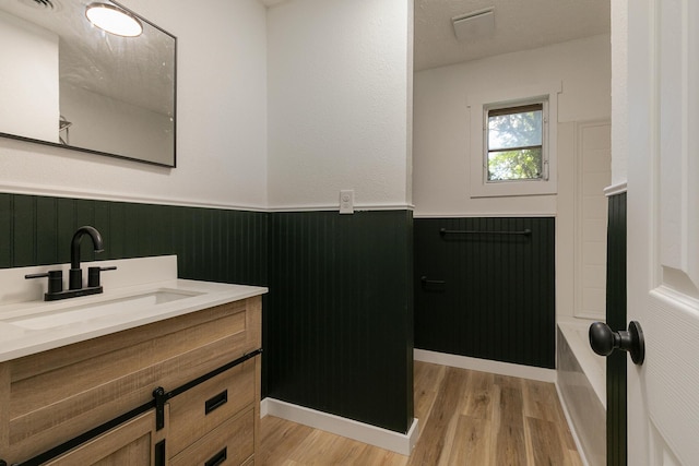 2716 W Elm St, Springfield, MO 65802 - bathroom with wainscoting, vanity, wood finished floors, wooden walls, and bathing tub / shower combination