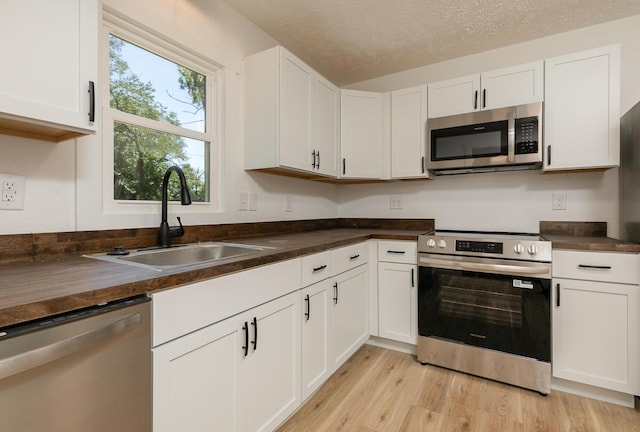 2716 W Elm St, Springfield, MO 65802 - kitchen featuring appliances with stainless steel finishes, white cabinets, light wood-type flooring, and a textured ceiling