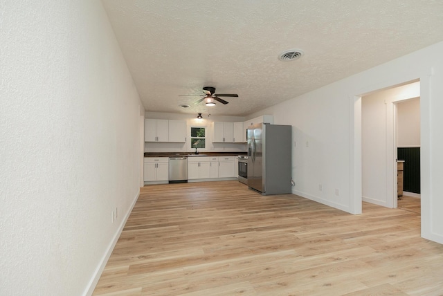 2716 W Elm St, Springfield, MO 65802 - kitchen featuring appliances with stainless steel finishes, dark countertops, ceiling fan, a textured ceiling, and light wood-type flooring