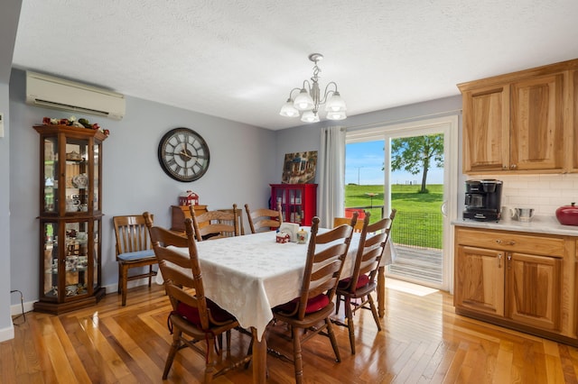 2616 Schupbach Rd, Clever, MO 65631 - dining area featuring a wall mounted AC, a chandelier, light wood-style floors, and a textured ceiling