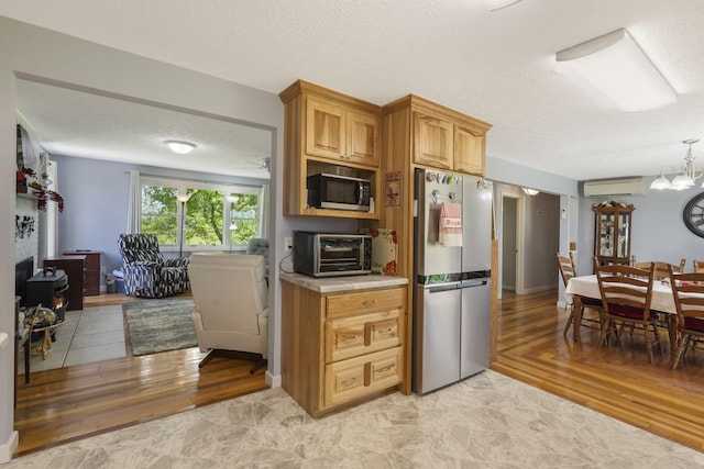 2616 Schupbach Rd, Clever, MO 65631 - kitchen featuring freestanding refrigerator, an AC wall unit, light countertops, a textured ceiling, and light wood-style flooring