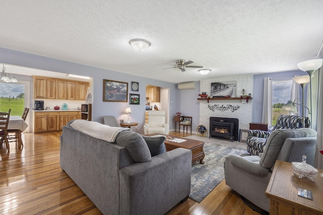 2616 Schupbach Rd, Clever, MO 65631 - living room with light wood-type flooring, ceiling fan, a brick fireplace, a textured ceiling, and a wall mounted air conditioner