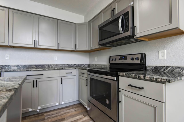 2525 New Hampshire Ave, Joplin, MO 64804 - kitchen with stainless steel appliances, gray cabinetry, light wood-type flooring, dark stone countertops, and a textured wall