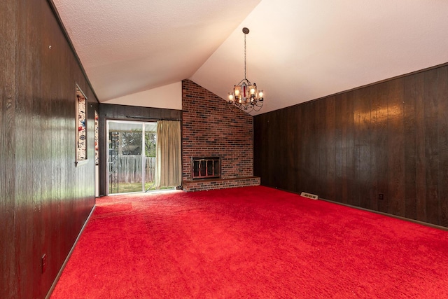 2311 E Meadow Dr, Springfield, MO 65804 - unfurnished living room with wooden walls, a chandelier, a brick fireplace, vaulted ceiling, and carpet flooring