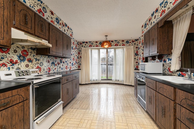 2311 E Meadow Dr, Springfield, MO 65804 - kitchen featuring white appliances, under cabinet range hood, wallpapered walls, a textured ceiling, and brick patterned floors