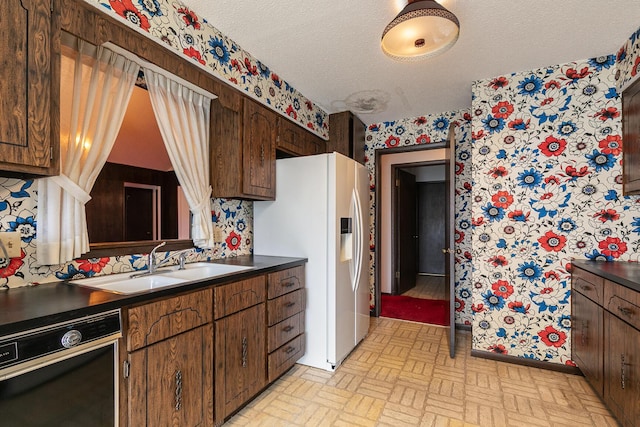 2311 E Meadow Dr, Springfield, MO 65804 - kitchen featuring dishwasher, wallpapered walls, white refrigerator with ice dispenser, brick patterned floors, and dark countertops