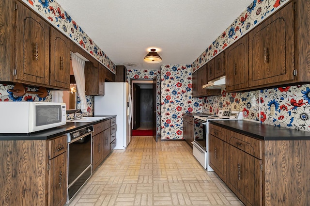 2311 E Meadow Dr, Springfield, MO 65804 - kitchen with white appliances, under cabinet range hood, wallpapered walls, brick patterned flooring, and dark countertops